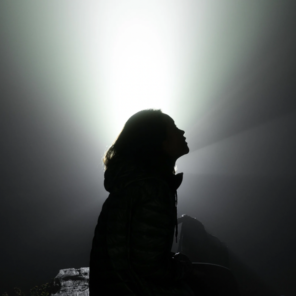 Eine junge Frau im Gegenlicht als dunkle Silhouette.