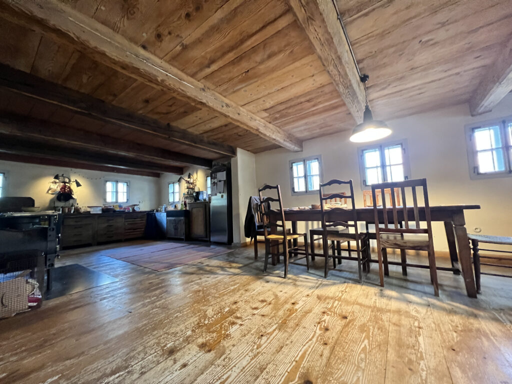Eine große Küche mit Holzboden und Holzdecke. Ein großer Tisch mit Stühlen.