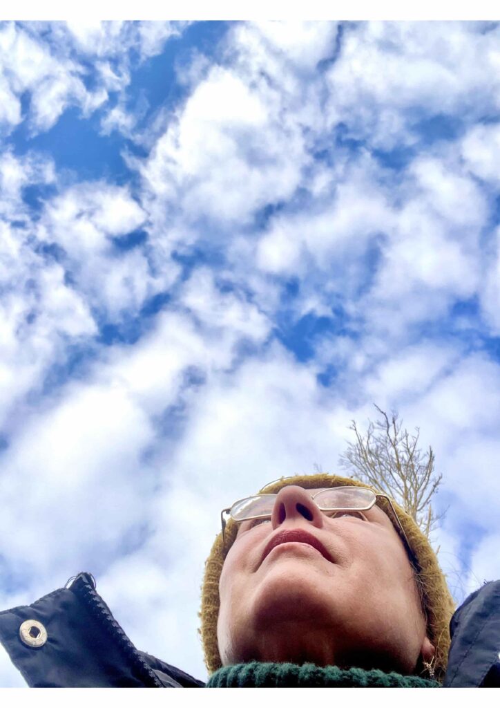 Eine Frau mit Brille schaut in den Himmel.