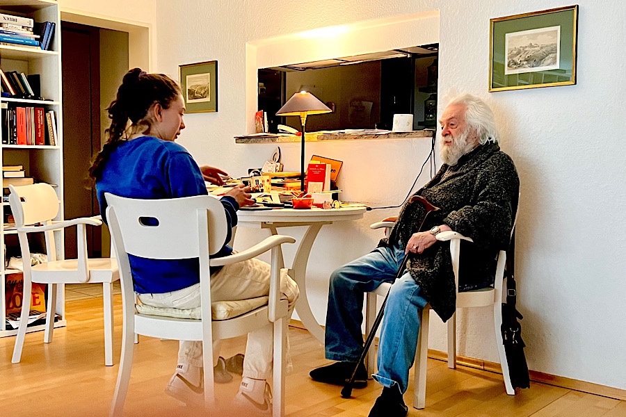 Ein alter Mann und eine sehr junge Frau sitzen an einem Tisch und unterhalten sich