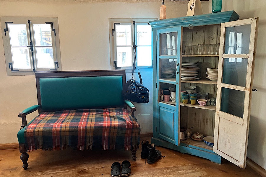 Eine Küchenecke mit blauem Geschirrschrank und grünem Sofa . 2 Fenster im Hintergrund.