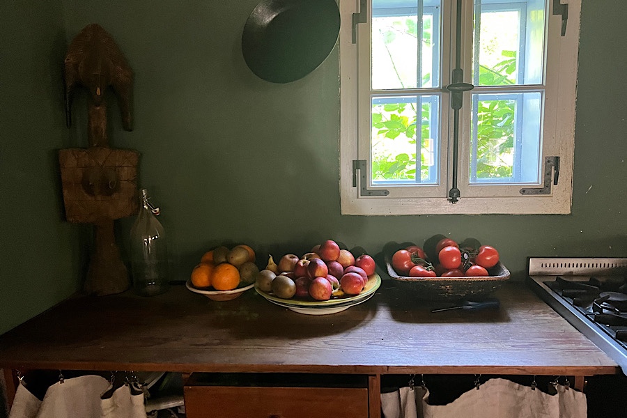 3 große mit Obst beladene Teller in einer Küche mit grüner Wand auf einer Holz-Ablage.